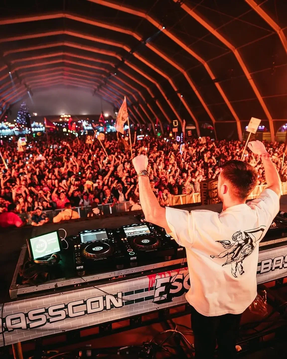 DJ performing to a crowd at Academy LA nightclub in Los Angeles with raised hands.