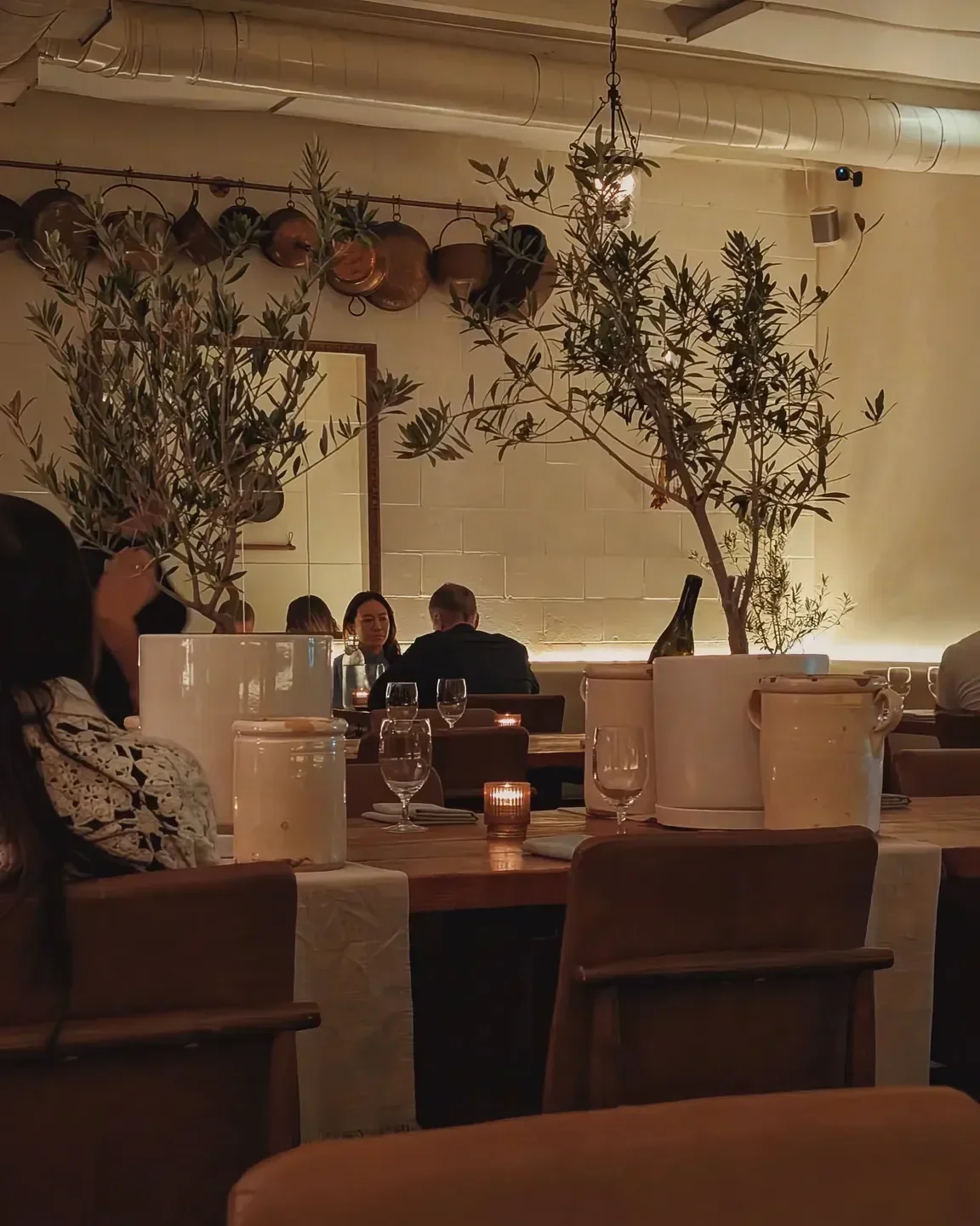 Elegant dining at Antico Nuovo in Los Angeles, featuring olive branches and warm lighting.