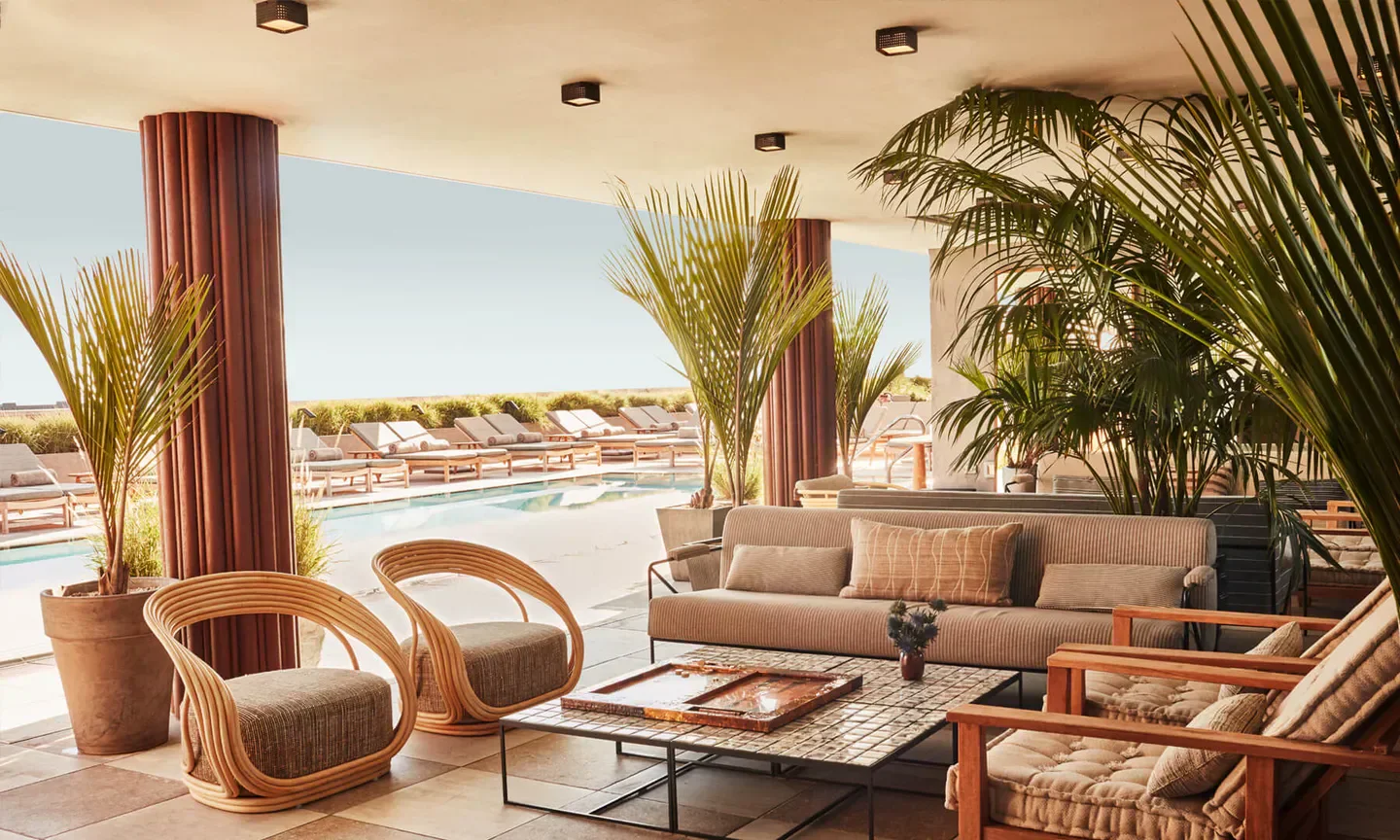 Outdoor seating at Calabra restaurant in Los Angeles, featuring a pool view and stylish decor.