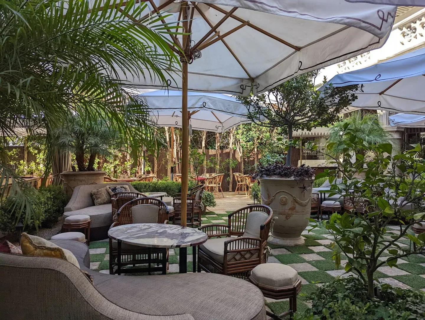 Charming outdoor dining area at Chateau Marmont in Los Angeles, under parasols and greenery.