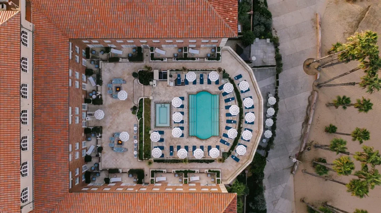 Club Casa beach club exterior aerial view with swimming pool, lounge chairs, and palm trees.