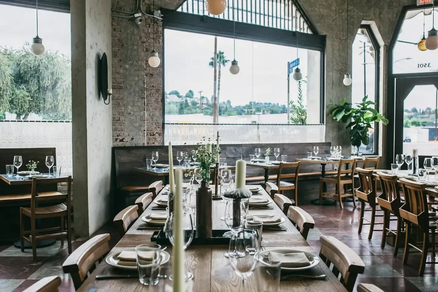 Interior dining at Dunsmoor restaurant in Los Angeles, featuring candlelit tables and a large window.