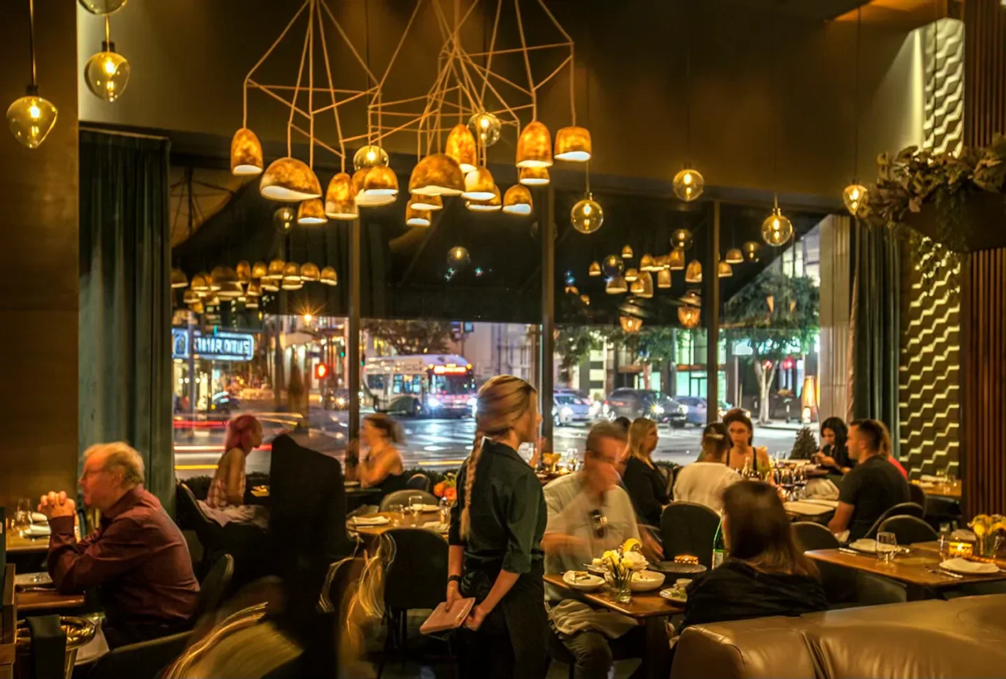 Inside Le Grand Restaurant in Los Angeles, with warm lighting and a view of the city.