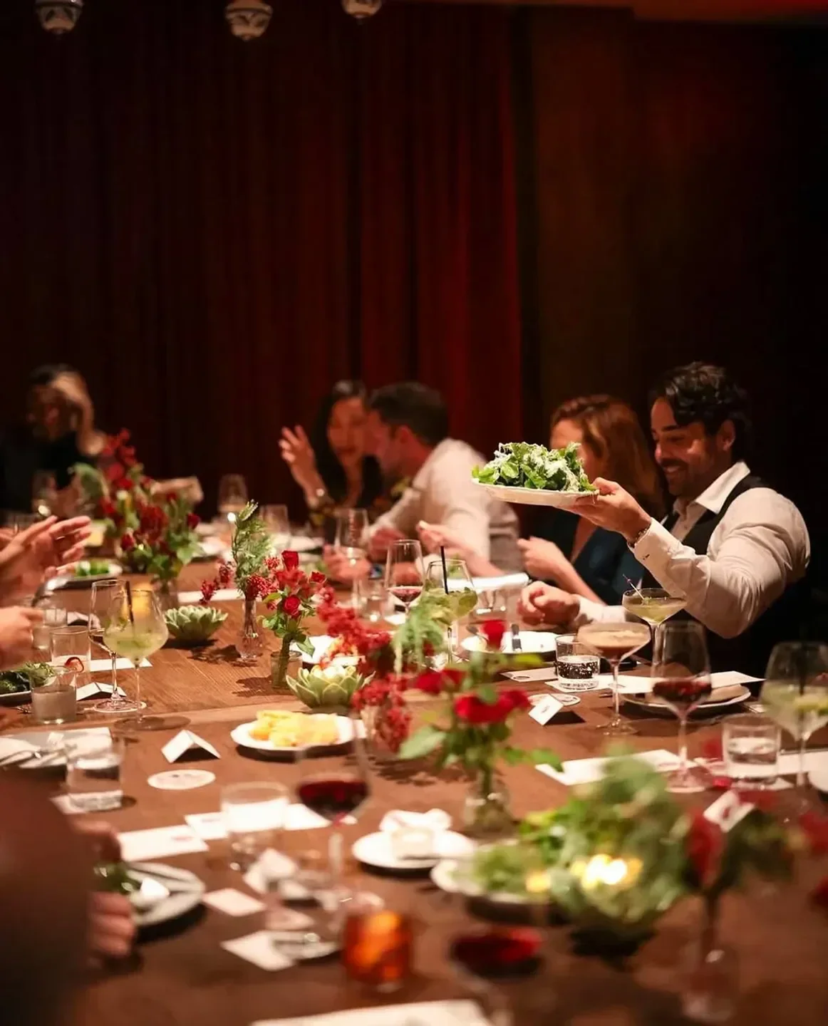 Dining scene at Mother Wolf in Los Angeles, featuring a server with salad and guests