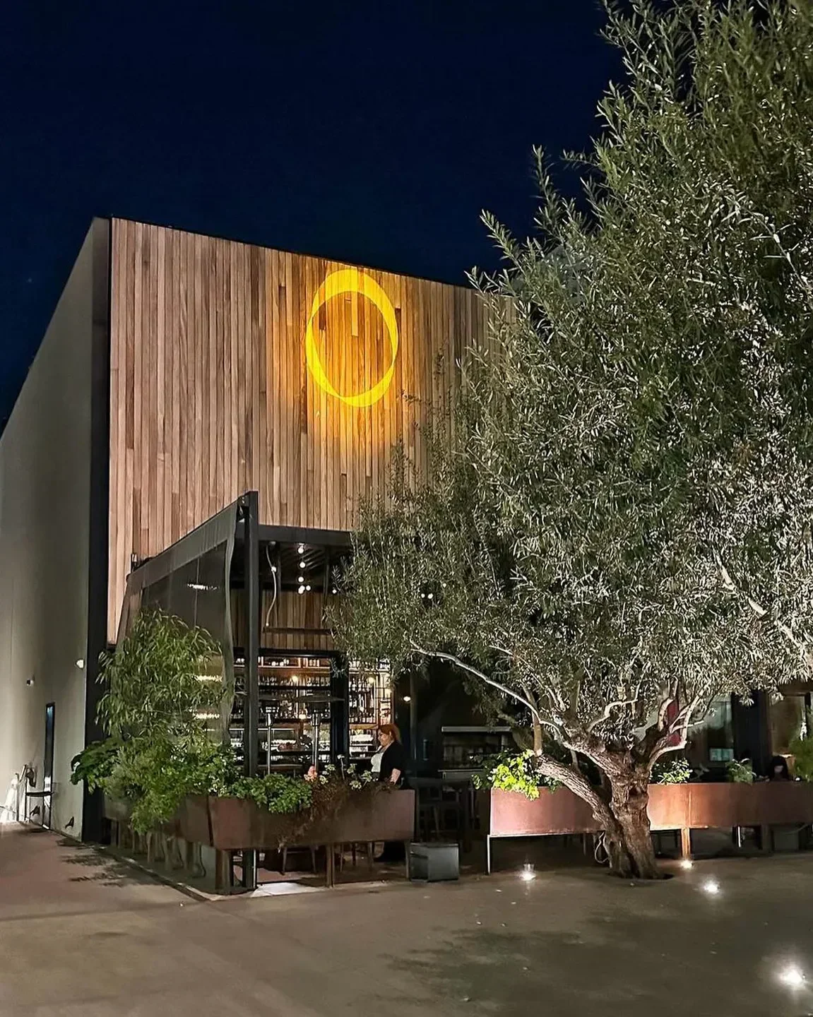 Exterior view of Otium restaurant in Los Angeles at night, with a modern design and lit logo.