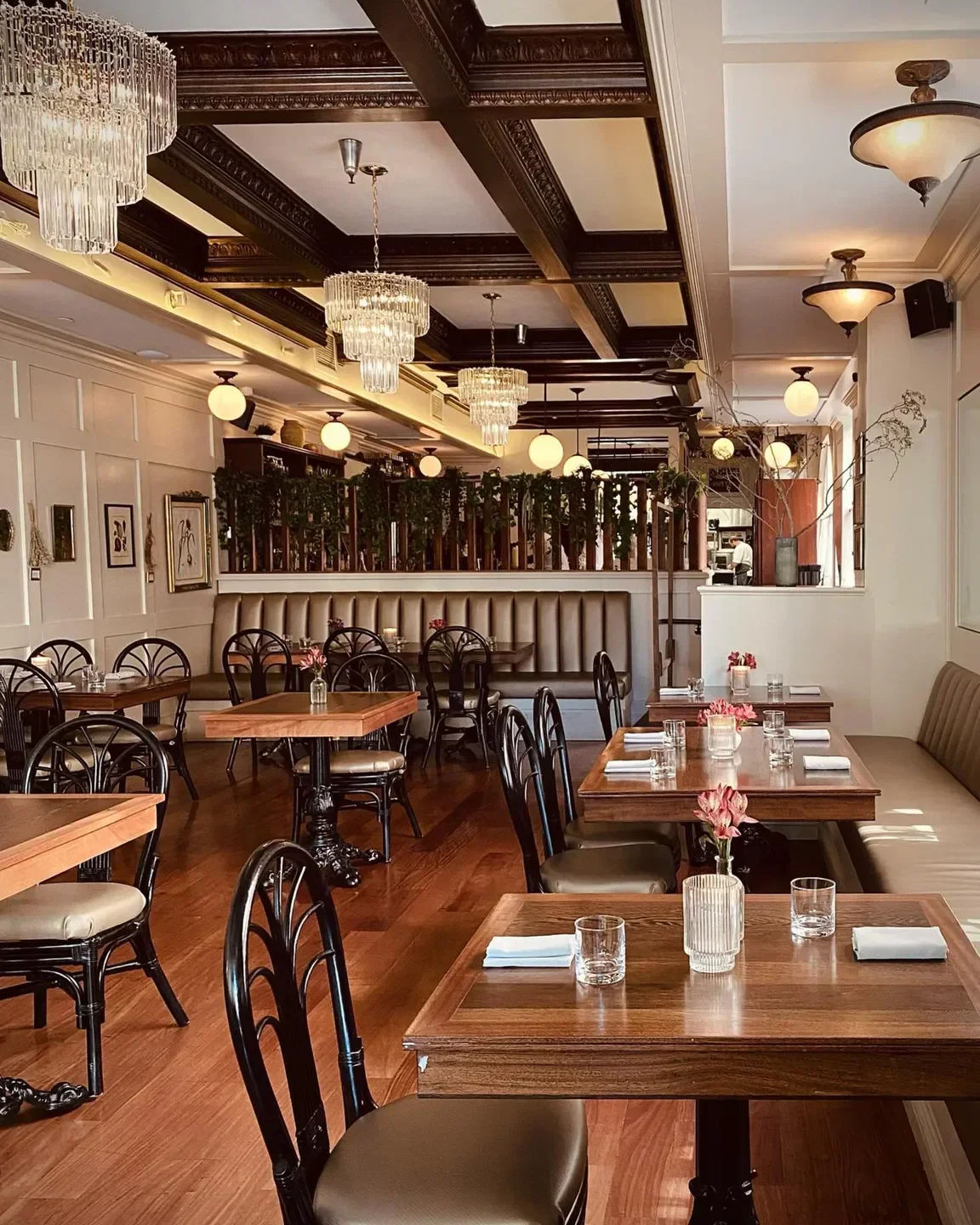 Elegant interior of Perle restaurant in Los Angeles, featuring chandeliers and wooden tables.