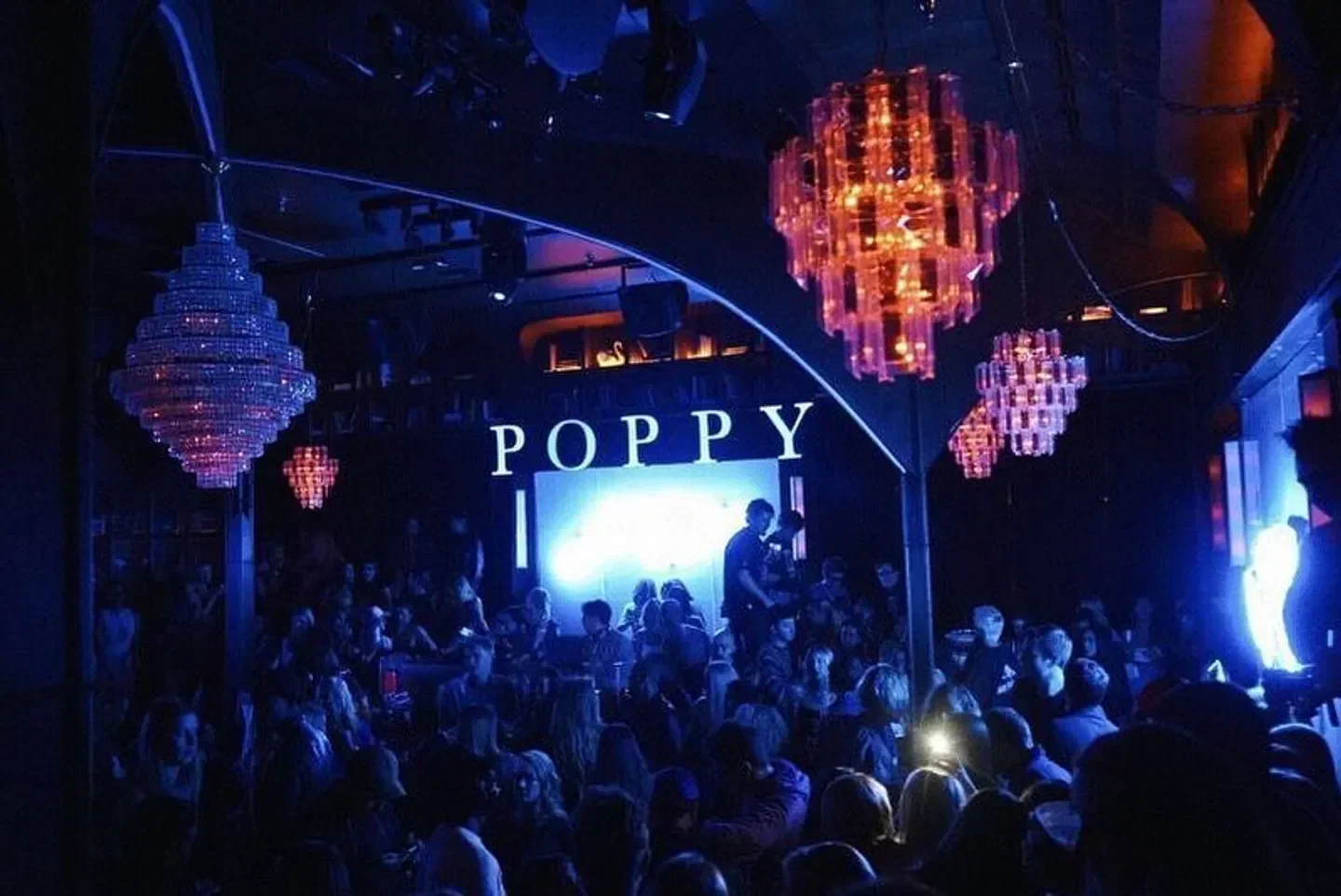 Inside Poppy Nightclub in Los Angeles, sparkling chandeliers over a crowd of people.