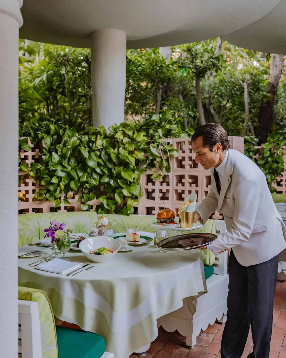 Server at The Polo Lounge in Los Angeles placing food on a table set for dining.
