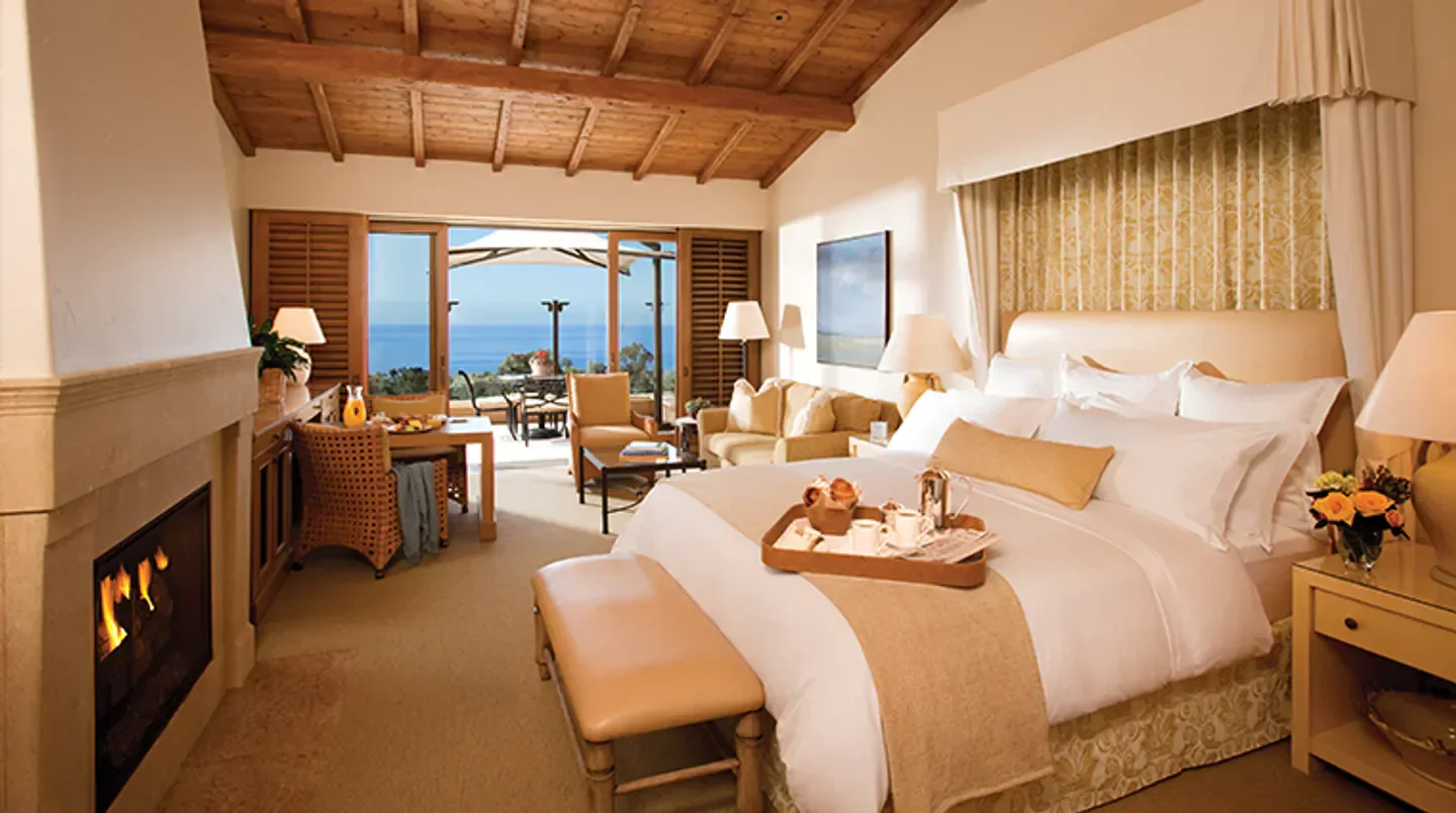 Luxury bedroom at The Resort at Pelican Hill in Los Angeles with ocean view and fireplace.