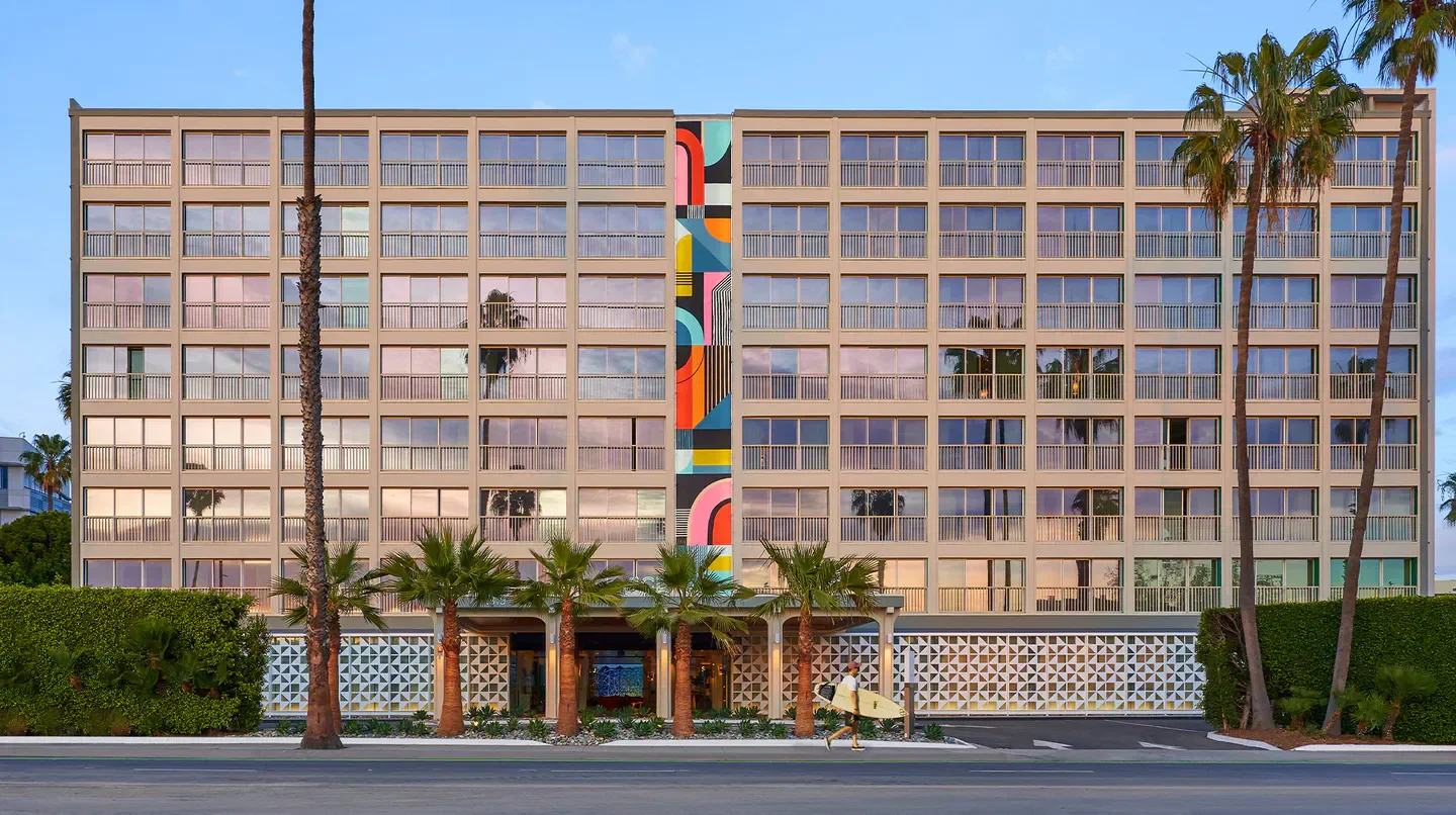 Exterior view of the Viceroy Santa Monica in Los Angeles, featuring palm trees and a colorful mural.